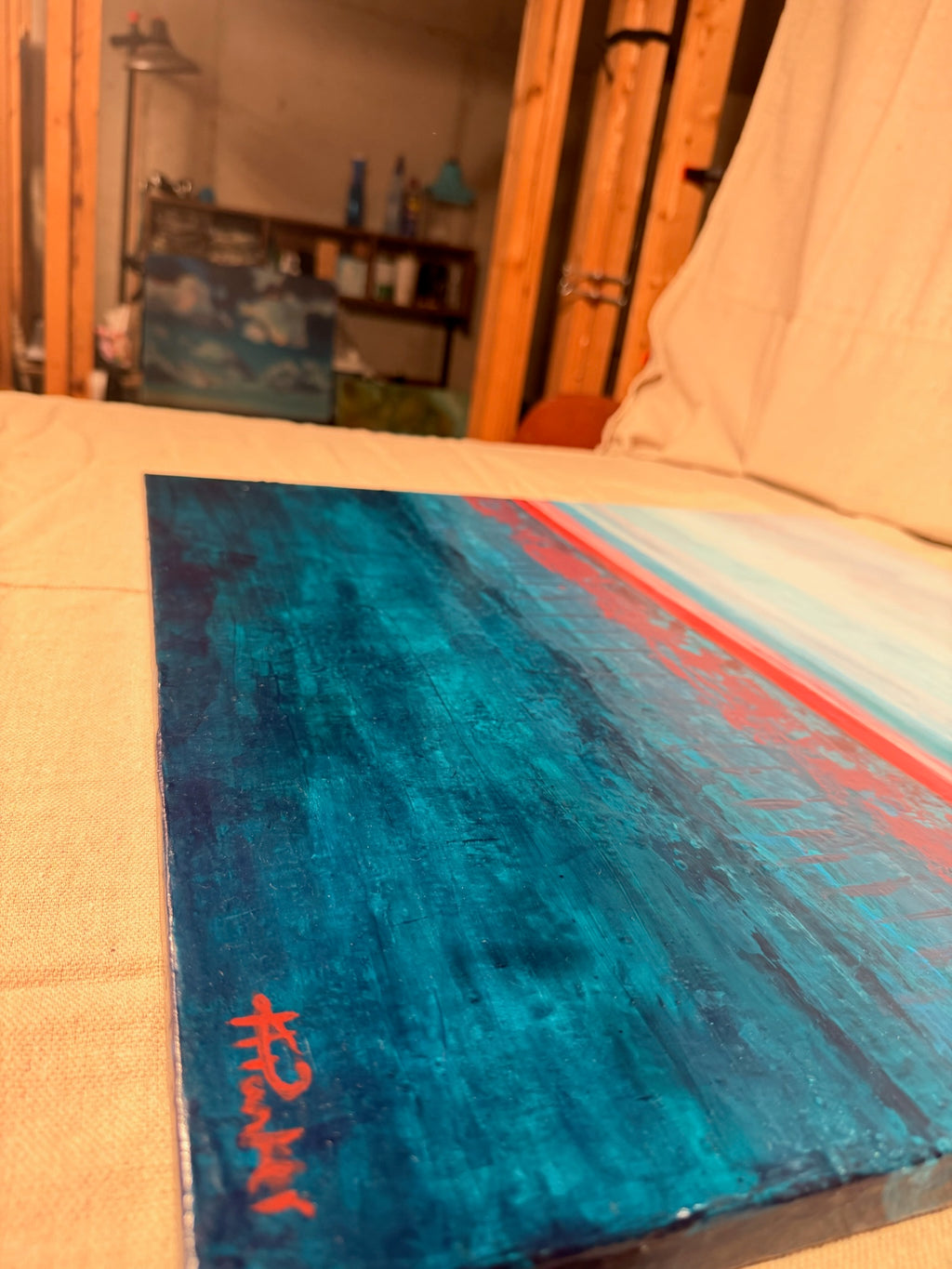 Angled close-up of the lower corner of Rest in Your Peace, showing textured teal paint and Kindra's red signature.