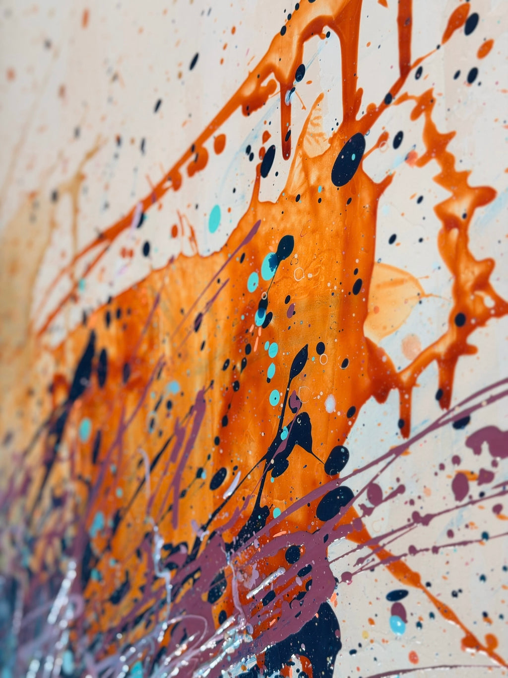 Close-up of I Have My Own Gravity: bold orange paint splashes with flung drips of navy, turquoise and lilac across pale canvas.
