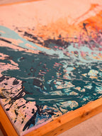 Angled close-up of I Have My Own Gravity showing sweeping dark teal and aqua splatter meeting the warm wooden frame.