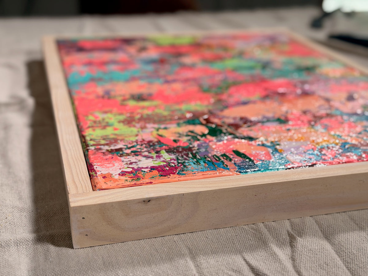 Low-angle view of Pretty Girls Walk lying flat, showing its raised, layered paint surface and the side of its pale wood frame.