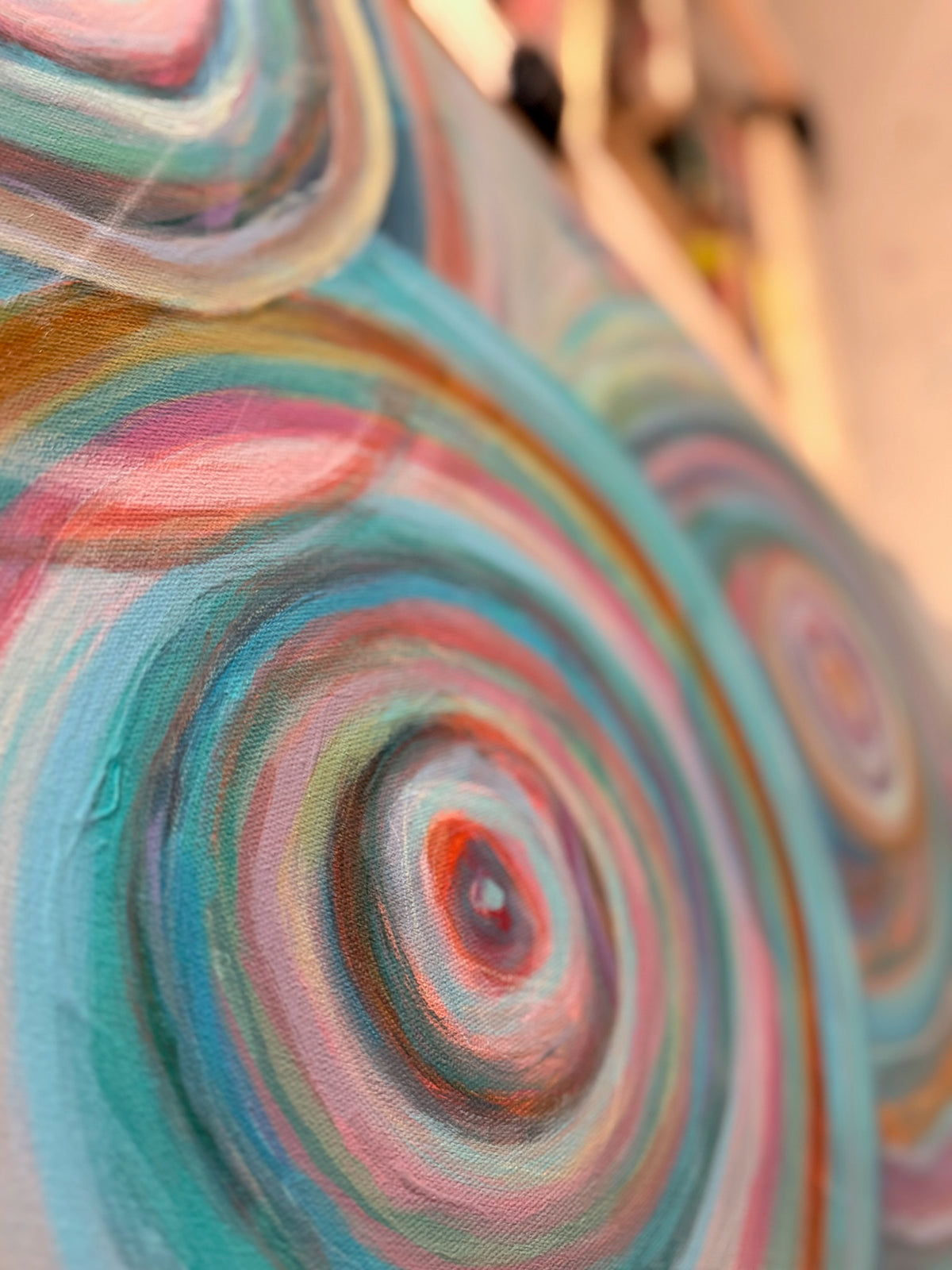 Close-up of Abundance showing nested rings of teal, blush, cream and copper paint spiraling out from a small red center.
