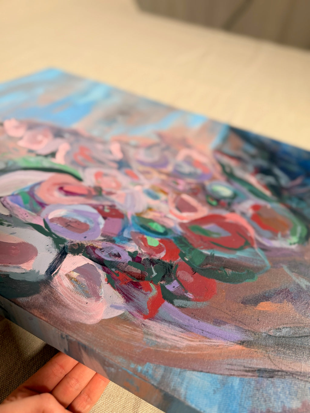 Angled close-up of In Those Ashes, A Garden Grows, held in hand, showing layered pink, red and lavender circles with dark green curving strokes.