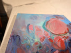 Angled view of Soul Nourished, I Bloom Anew lying flat, showing a large salmon-pink shape outlined in teal amid hazy blue and mauve circles.