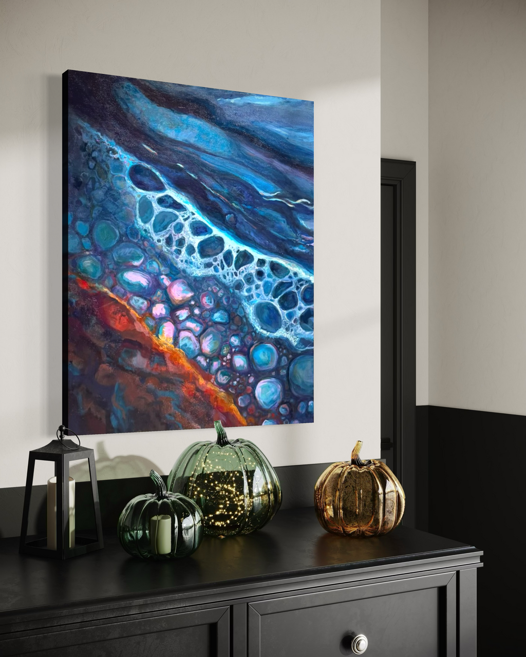 Polished By The Rough Torrent shown above a black dresser with glass and gold pumpkins, its deep blue, turquoise and orange layers catching the light.