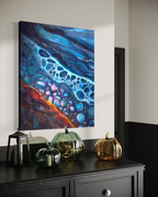 Polished By The Rough Torrent shown above a black dresser with glass and gold pumpkins, its deep blue, turquoise and orange layers catching the light.