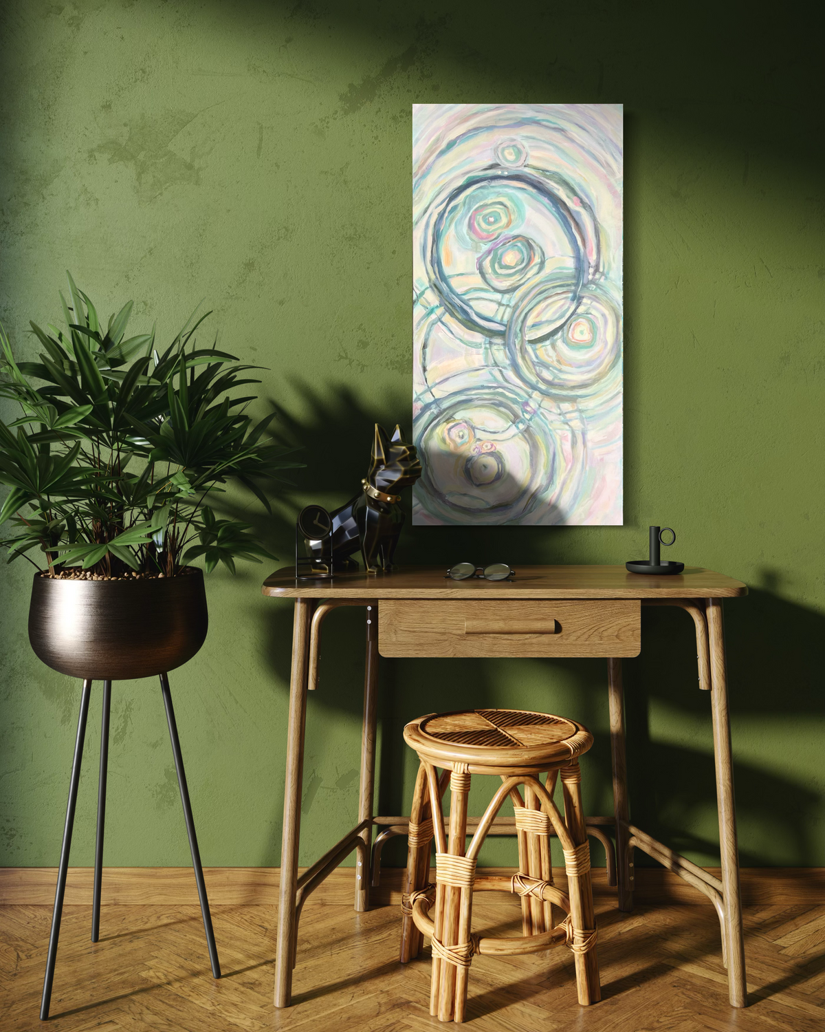 Grace, a tall abstract in mixed media on stretched canvas: soft ripple circles in slate blue, sage and blush on a pale pearly background, shown above a desk on a green wall.
