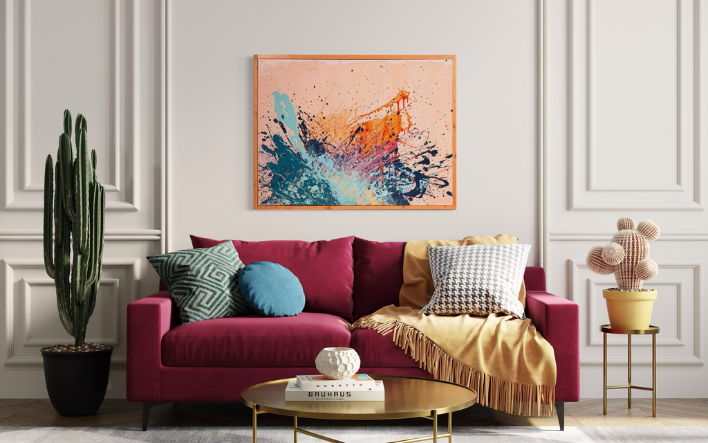 I Have My Own Gravity, an abstract in mixed media on stretched canvas: explosive orange, navy, aqua and pink splatters on a peach background, shown above a magenta sofa.
