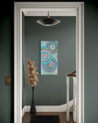 Abundance seen through a white doorway, hanging in a dark green hallway beside a tall vase of pampas grass.
