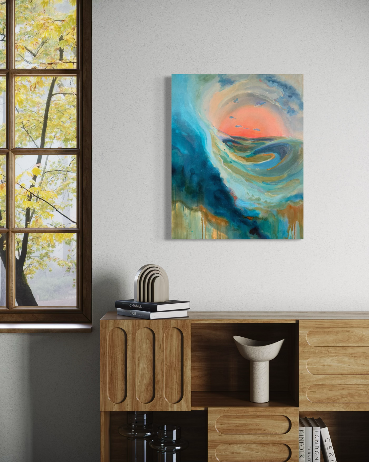 As The Path Unfolds, an abstract in mixed media on stretched canvas: a deep teal wave curls around a coral sun with drips of ochre and blue, shown above a wooden cabinet.