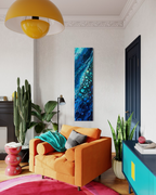 Stream of Consciousness, a tall, narrow painting in mixed media on stretched canvas: a diagonal river of turquoise bubbles through deep blue, shown above an orange sofa.