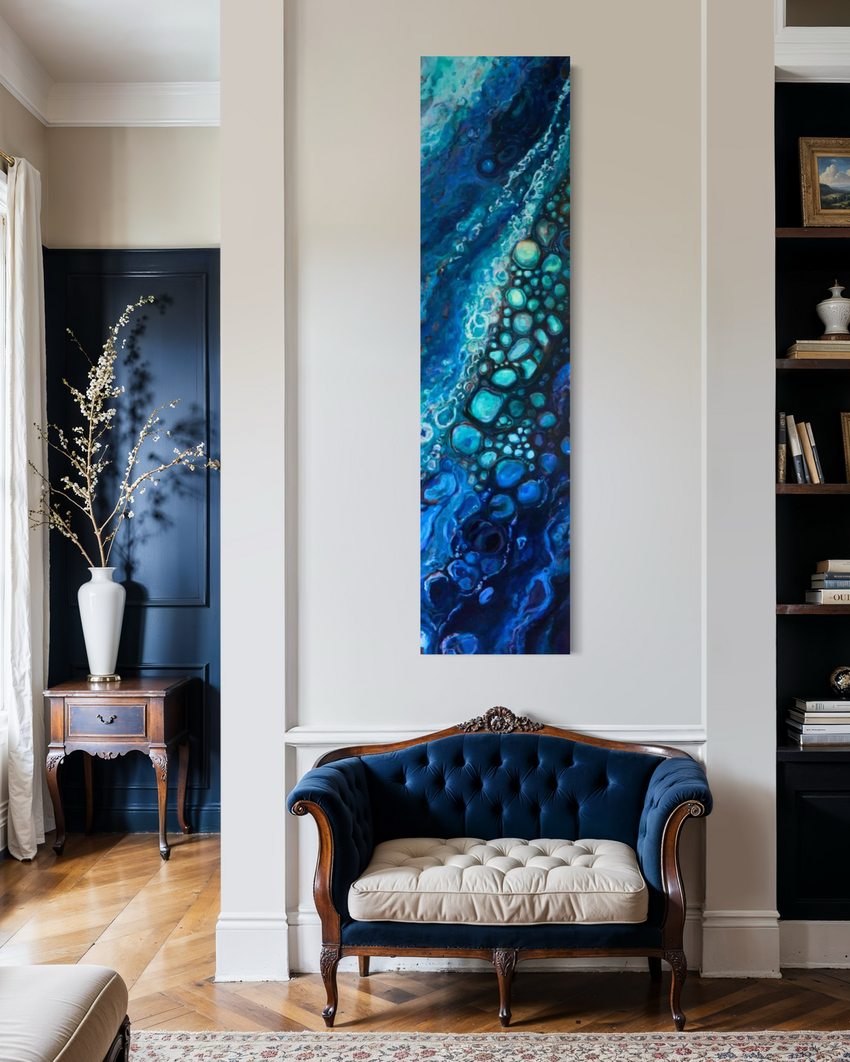 Stream of Consciousness hanging tall on a white pillar above a navy tufted settee, its ribbon of aqua and cobalt bubbles flowing down the canvas.