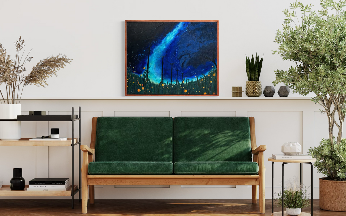 The View From The Grass, a night scene in mixed media on stretched canvas: a turquoise Milky Way over dark grass and golden fireflies, in a copper frame above a green sofa.
