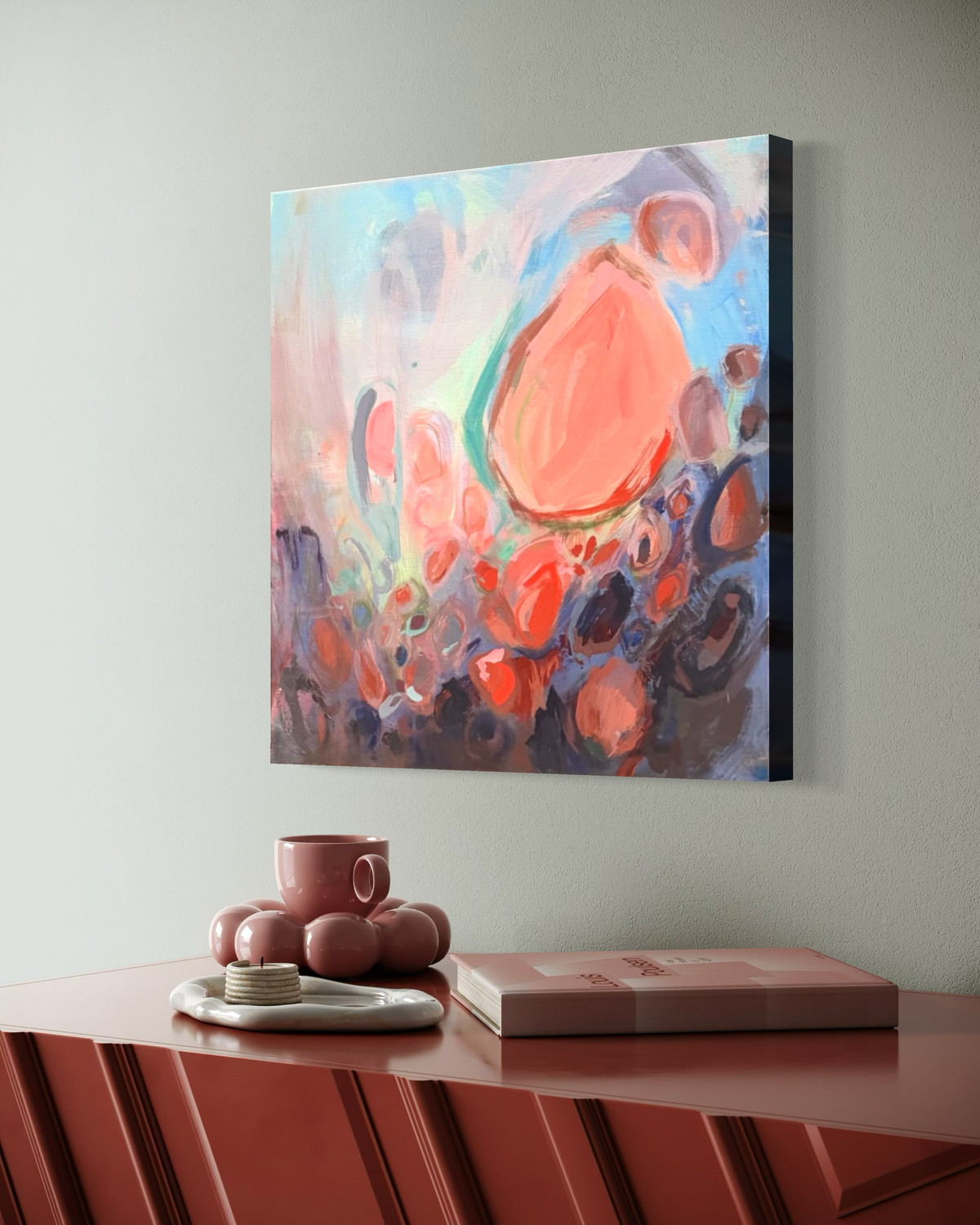 Soul Nourished, I Bloom Anew shown at an angle on a sage wall above a terracotta sideboard, its big coral form glowing over dusky blue and rose circles.